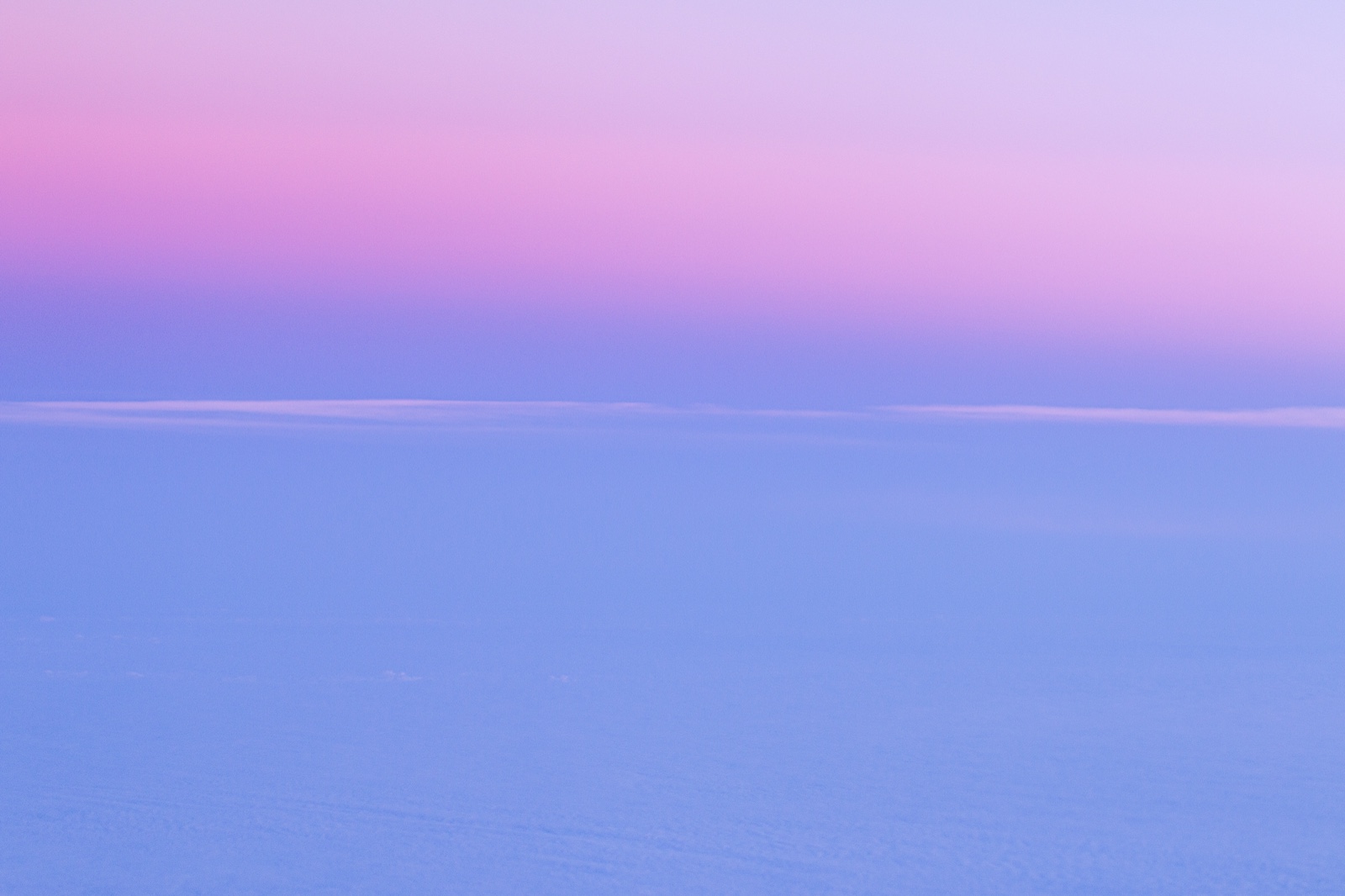 Superficie de nubes en tonos azul lavanda bajo un cielo rosa malva al amanecer; una línea finísima de nube separa ambos campos de color, sin ninguna otra referencia.