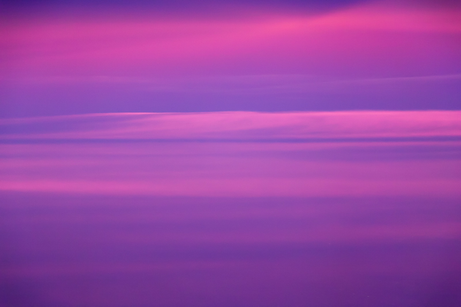 Campo de color magenta y violeta atravesado por bandas horizontales de nube, sin horizonte ni referencia de escala.